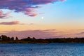 Sunset over the lake with the moon on the horizon