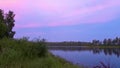 Sunset over the lake. Pink clouds lit by the setting sun. Calm and pacification of nature