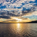 Sunset over the lake, reflection of the sun with clouds, dramatic sky and golden colors Royalty Free Stock Photo