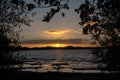 Sunset over the lake, view through the black tree silhouettes on Royalty Free Stock Photo