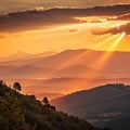 Sunset Over Layered Mountains with Sun Rays Breaking Through Clouds Royalty Free Stock Photo