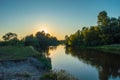Sunset over the meandering river, which is hidden behind the crown of trees growing on the banks. Photos from the shore. Scenery o Royalty Free Stock Photo