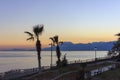 Sunset over the Mediterranean Sea. Palm trees and mountains against the sunset sky