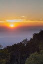 Sunset over the misty cloudy sky with tree and mountain view.