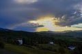 Sunset over the mountains, village, green hills across cloudy sky, and sunlight. Natural background. Copy space. High quality phot Royalty Free Stock Photo