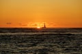 Sunset over the ocean with light reflecting on ocean waves moving with boats on the water in the distance Royalty Free Stock Photo