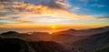 Sunset over ocean with rugged mountain coast and beautiful color in clouds Royalty Free Stock Photo