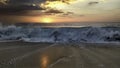 Sunset over the ocean from the shore of NazarÃÂ© beach, Playa do Norte, Portugal. The waves break on the shore reflecting the Royalty Free Stock Photo