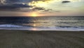 Sunset over the ocean from the shore of NazarÃÂ© beach, Playa do Norte, Portugal. The waves break on the shore reflecting the Royalty Free Stock Photo