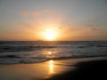 Sunset over Pacific ocean with large cargo ship in the background and waves rolling in on Ocean Beach