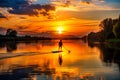 A sunset over a river, silhouetting a lone paddleboarder Royalty Free Stock Photo