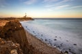 Sunset over a rocky coastline, leading to a lighthouse sitting atop cliffs. Montauk State Park, New York