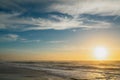 Sunset over the sea, beautiful sand beach, blue sea, blue sky with sun setting down the horizon Royalty Free Stock Photo