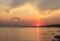 Sunset over the sea. Reflection of the sun in water. Silhouette of paraglider flying in the sky. Sunset beach in a summer evening