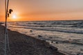 Sunset over the sea. Stones and fishing rods on the foreground Royalty Free Stock Photo