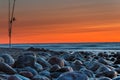 Sunset over the sea. Stones and fishing rods on the foreground Royalty Free Stock Photo