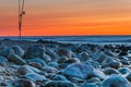 Sunset over the sea. Stones and fishing rods on the foreground Royalty Free Stock Photo