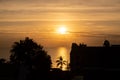 Sunset over the sea in the tropics, sunset sun in the clouds, in the foreground the contours of palm trees Royalty Free Stock Photo