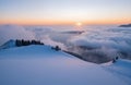 A sunset over a snowy mountain range with trees and clouds Royalty Free Stock Photo