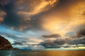 Sunset over stormy clouds across the water reflecting dark and looming dramatic sky moody Royalty Free Stock Photo