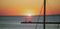 Sunset over Tinos island, Cyclades, Greece. Ship mast, beacon silhouette golden sun dives into sea