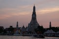 Sunset over the Wat Arun Buddhist Temple. A small passenger ferry at the pier of the Chao