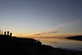 Sunset over water with three people in the shadow with whisp of clouds Royalty Free Stock Photo