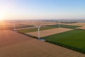 Sunset over the windmills. Wind turbines over fields of wheat and sunflowers Royalty Free Stock Photo