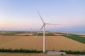 Sunset over the windmills. Wind turbines over fields of wheat and sunflowers Royalty Free Stock Photo