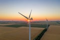 Sunset over the windmills. Wind turbines over fields of wheat and sunflowers Royalty Free Stock Photo