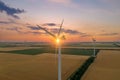 Sunset over the windmills. Wind turbines over fields of wheat and sunflowers Royalty Free Stock Photo