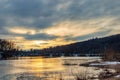 Sunset over the winter river. Thawing in the ice of a frozen river