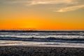 Sunset through the pacific surf. Top of the waves are being blow off in front of the sun.