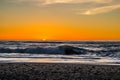 Sunset through the pacific surf. Top of the waves are being blow off in front of the sun.