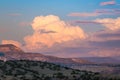 Sunset paints cumulus clouds and thunderheads in soft colors of pink, purple and peach over a colorful desert landscape Royalty Free Stock Photo
