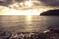 Sunset pebbles beach with dramatic golden sky and water surface on coastline Royalty Free Stock Photo