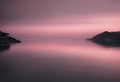 a sunset photo taken from across the water with a pink sky in the background Royalty Free Stock Photo