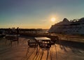Sunset at pier in harbor cafe table and chair on fron background big cruise ship and people relaxing Tallinn new port Baltic sea Royalty Free Stock Photo
