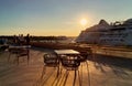 Sunset at pier in harbor cafe table and chair on fron background big cruise ship and people relaxing Tallinn new port Baltic sea Royalty Free Stock Photo