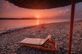 Sunset in pink with sunbed and parasol on the beach and Mountain Tahtali in the background. Tourism and recreation in the