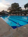 sunset at the pool surrounded by chairs and trees Royalty Free Stock Photo