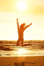 Sunset portrait young woman jumping for joy at the beach Royalty Free Stock Photo