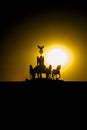 Berlin, Sunset Quadriga at Brandenburg Gate. Silhouette of Quadriga in backlight at sunset with yellow sun ball and orange sky