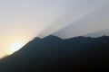 Sunset and rays of light in the sky from behind a mountain Royalty Free Stock Photo