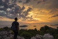 Man standing outdoor on mountain with backpack looking at sunset over sea in Croatia Europe. Royalty Free Stock Photo