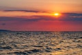 Sunset red sun in clouds over sea with waves on water, dark clouds Royalty Free Stock Photo