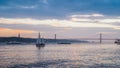 Sunset on River Tagus, Lisbon, Portugal with 25 April Bridge in background and boats Royalty Free Stock Photo