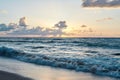 Sunset at the rocky sea. Turquoise water in the ocean in the evening.Yellow sky with small clouds and blue waves at sandy beach at Royalty Free Stock Photo