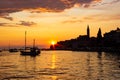 Sunset in Rovinj, Croatia, with a boat sailing in the Adriatic Sea and the sunrays reflected on the water, with the old town at Royalty Free Stock Photo