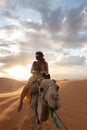 Sunset in Sahara desert with a woman in a camel Royalty Free Stock Photo